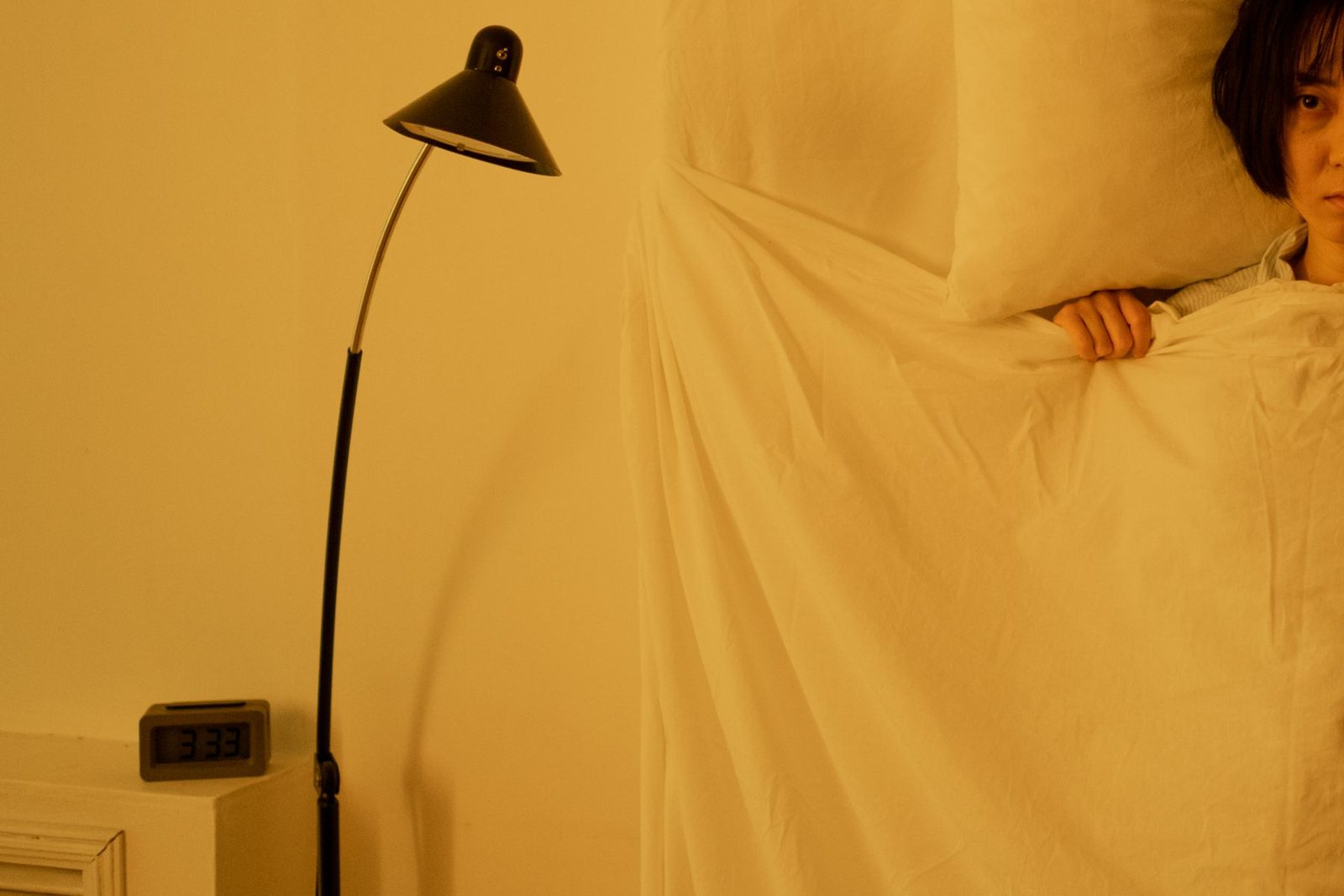 A woman sitting up in bed at night, unable to sleep