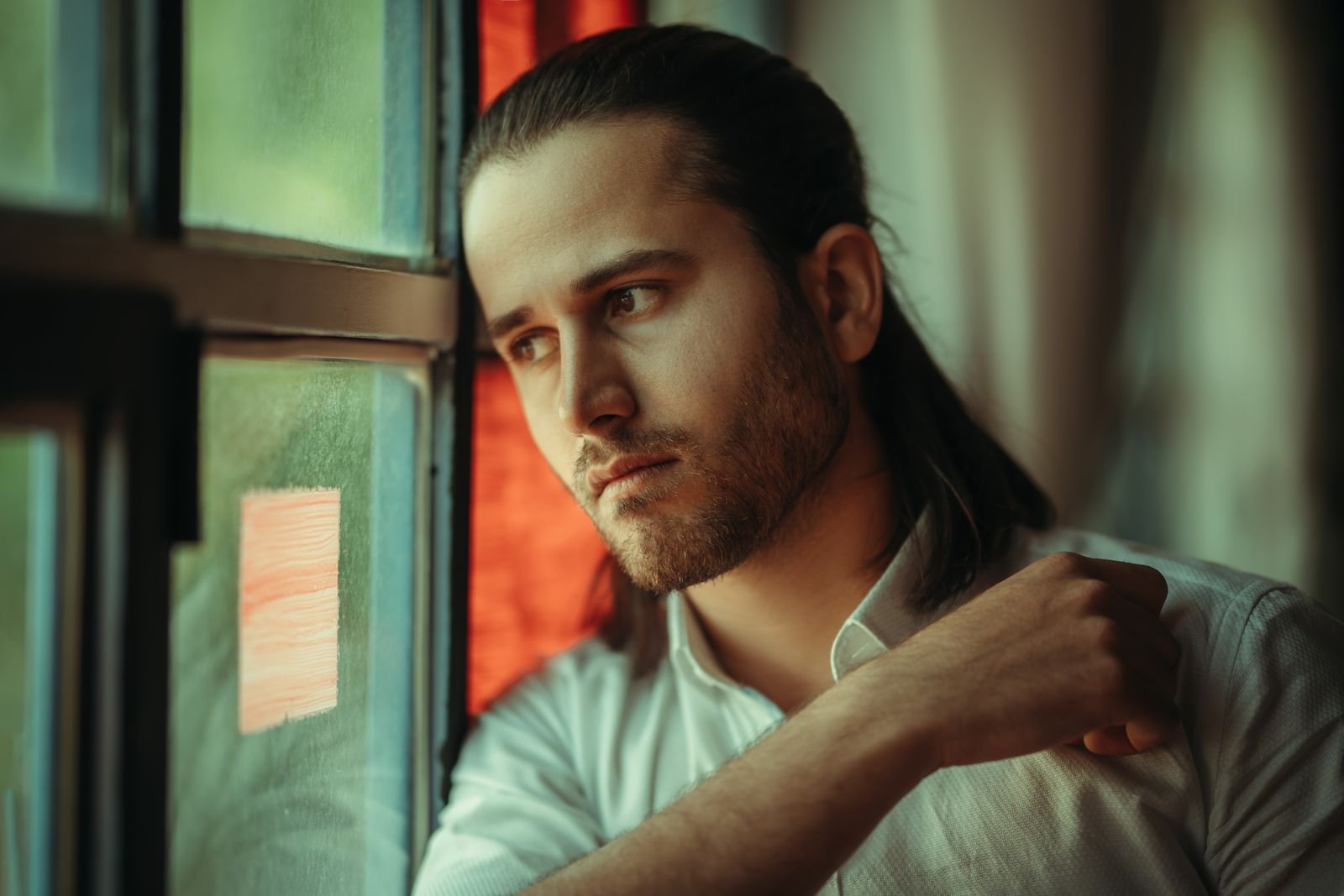 A man gazing out a window, lost in thought