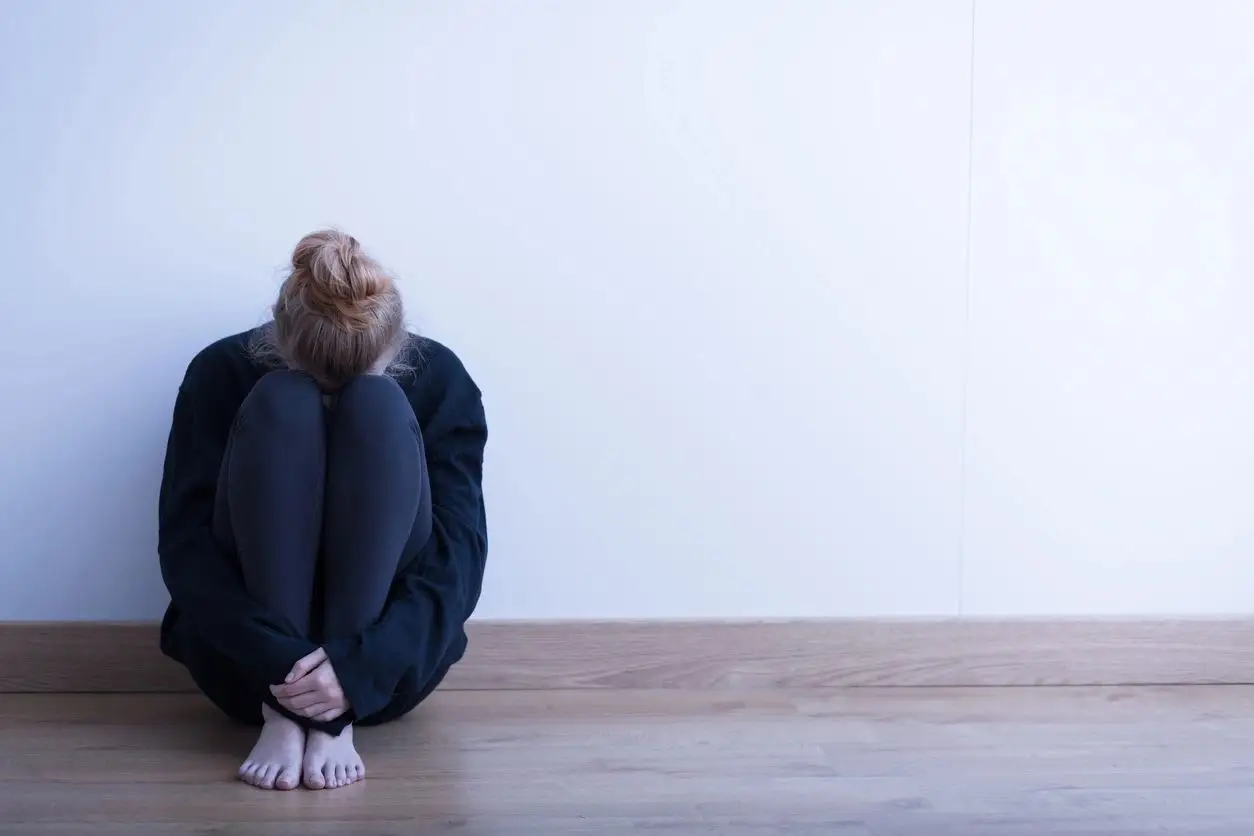 A woman sitting on the floor with her head down.