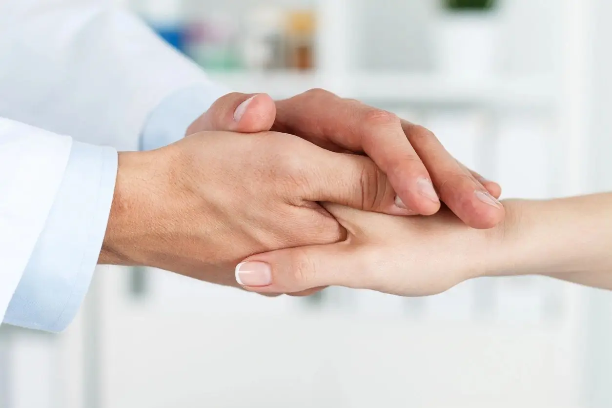 A person holding another persons hand in front of a wall.