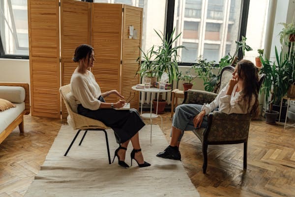 Two people sitting in chairs talking to each other.