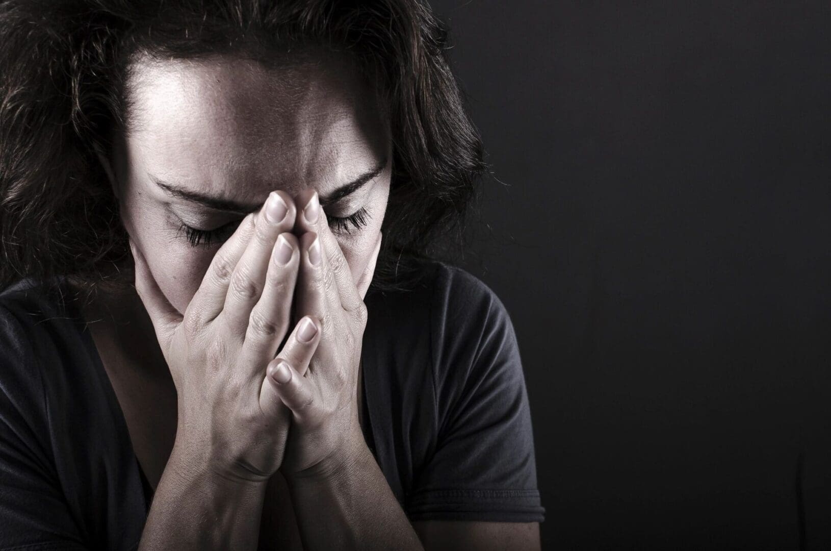 A woman is holding her hands to her face.